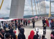 HUT RI ke-77, Ratusan Pemuda Bentangkan Bendera Merah Putih Sepanjang 770 Meter di Jembatan Teluk Kendari