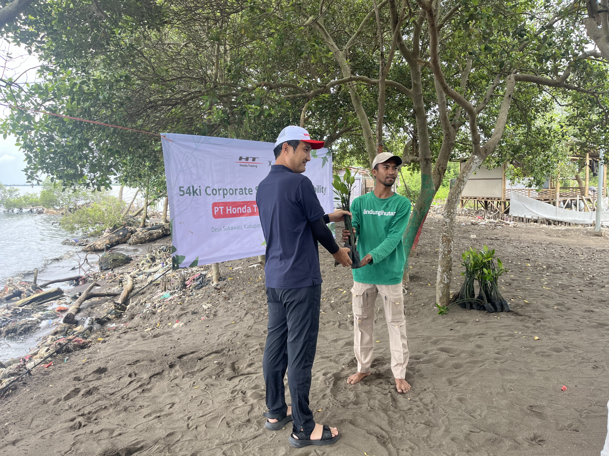 Penyerahan bibit mangrove secara simbolis oleh Presiden Direktur, Jumpei Suemoto (kiri) secara kepada mitra petani/masyarakat lokal, Bawi (kanan).